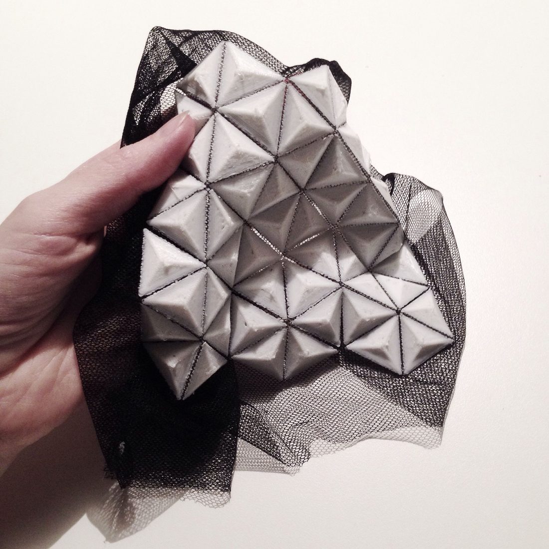 PLA rigid filament: a printed triangular lattice on black netting, held in a hand