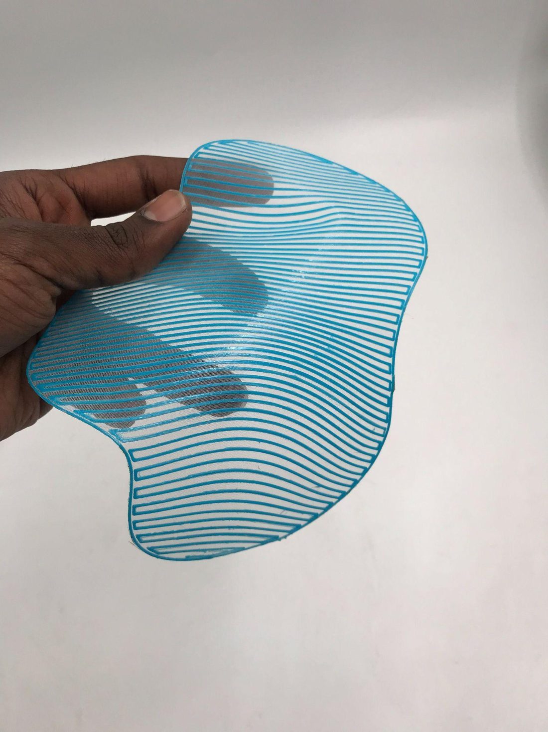 A single Moiré Drops element: blue printed lines on fine white mesh, held in a hand